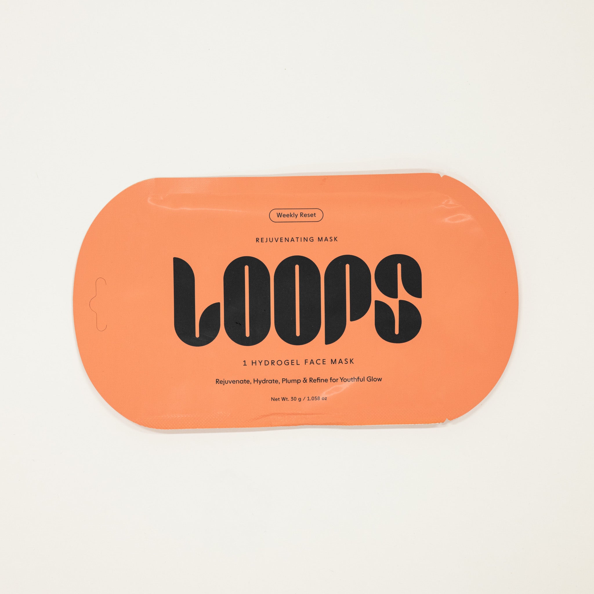 Orange packaging of LOOPS hydrogel face mask on a beige background