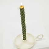 Green twisted candle on a white stand against a white background