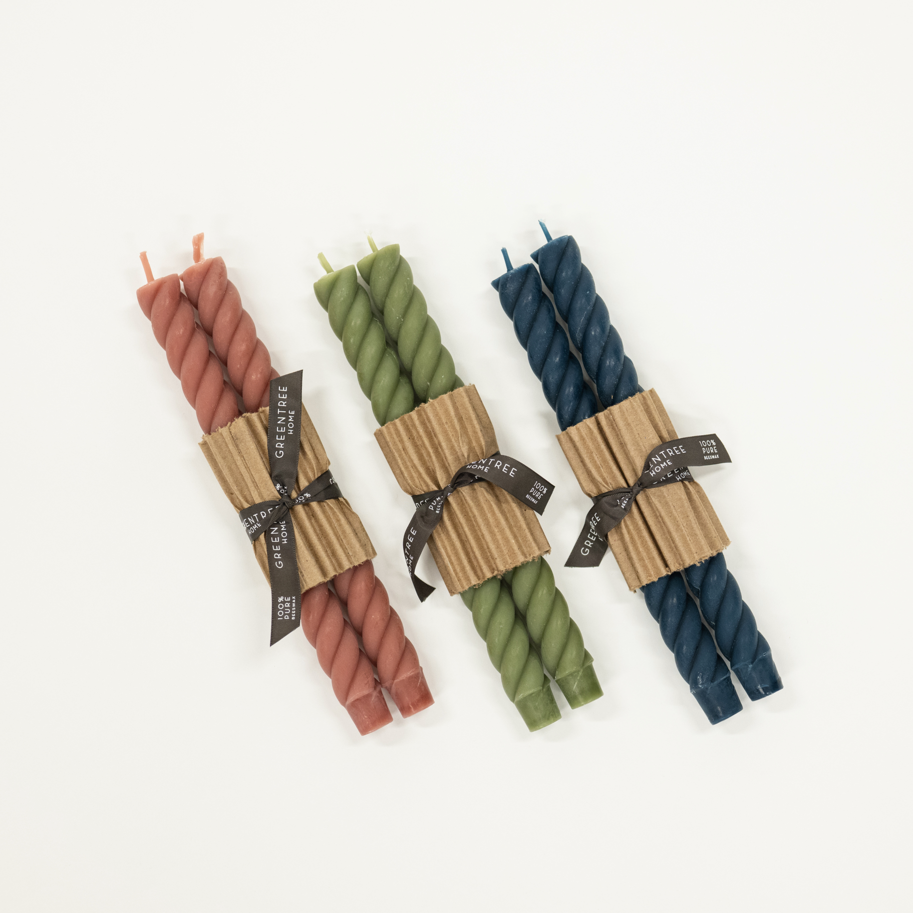 Three sets of twisted candles in pink, green, and blue with brown paper wrapping on a white background.