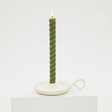 Green twisted candle on a white stand against a white background