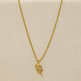 Gold necklace with a feather pendant on a beige background