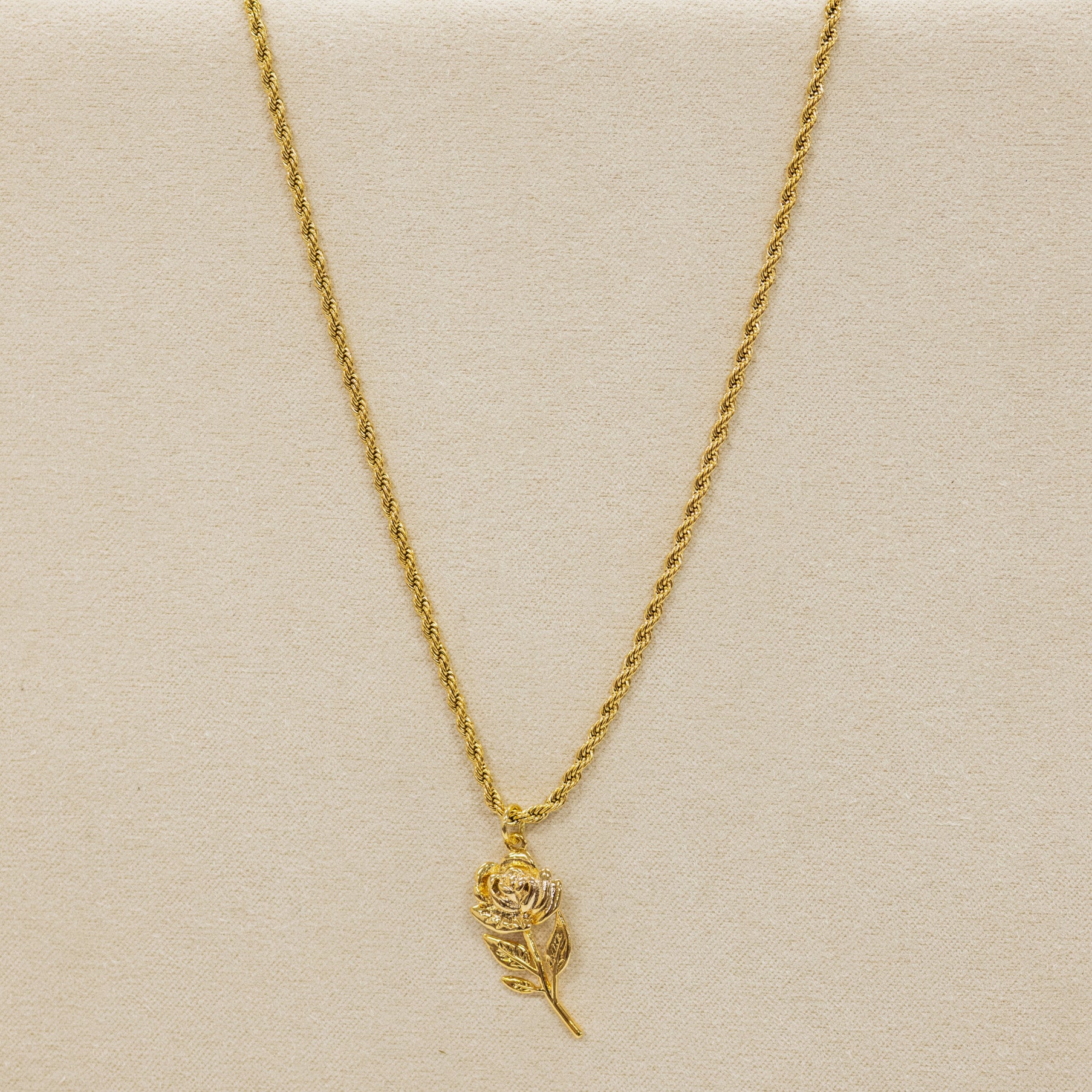 Gold necklace with a feather pendant on a beige background