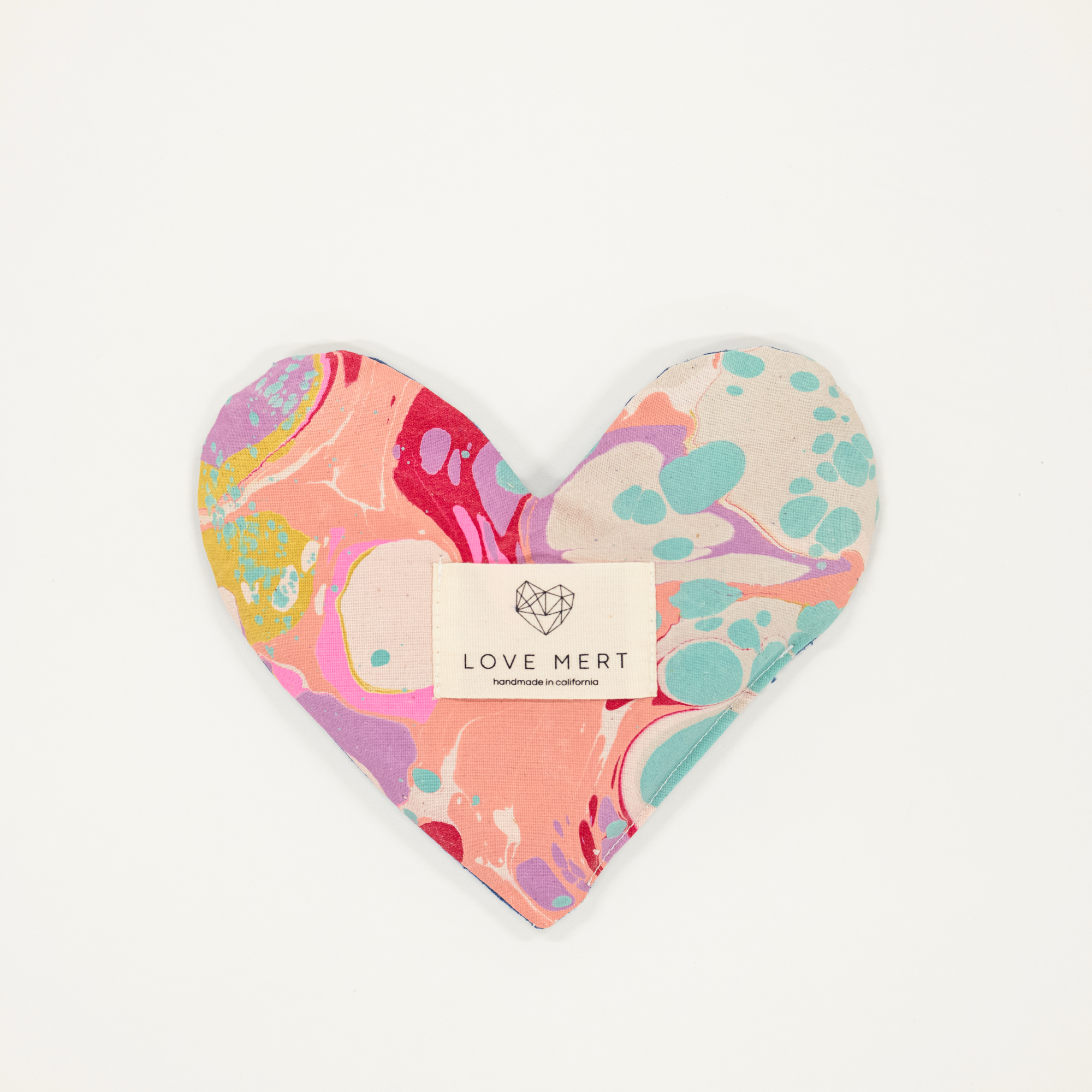 Heart-shaped pillow with colorful abstract pattern and 'LOVE MERT' label on a white background
