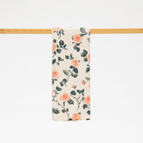 Floral patterned towel hanging on a wooden rod against a white background