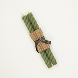 Green twisted candles wrapped in brown paper with a label on a white background