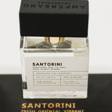 Perfume bottle labeled 'Santorini' with black cap on a dark surface