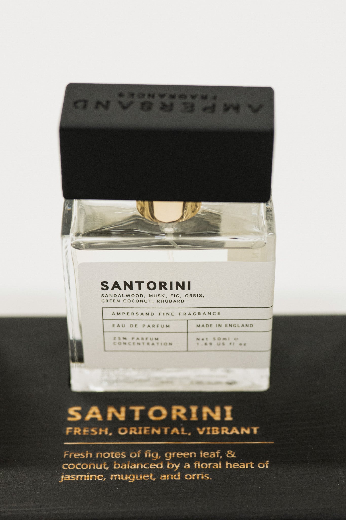 Perfume bottle labeled 'Santorini' with black cap on a dark surface