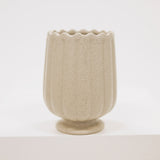 Beige ceramic vase with textured surface on a white background