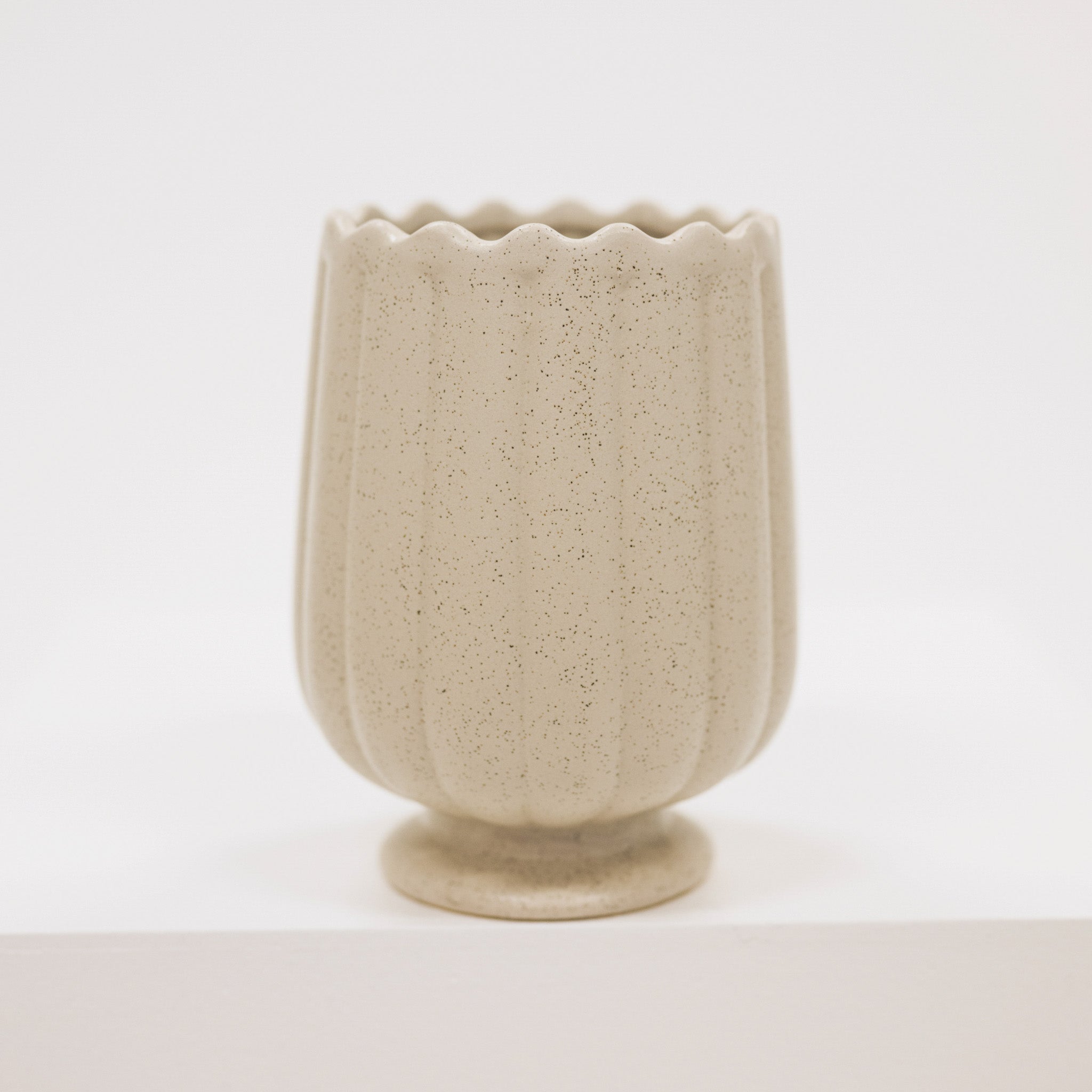 Beige ceramic vase with textured surface on a white background