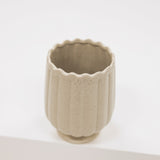 Beige ceramic vase with textured surface on a white background