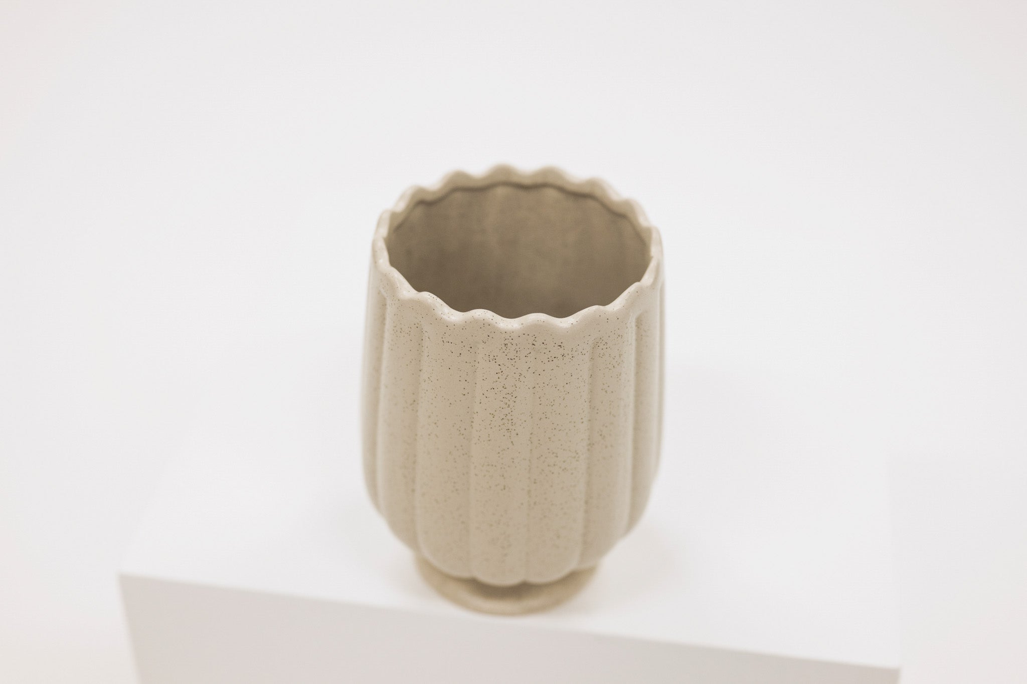 Beige ceramic vase with textured surface on a white background