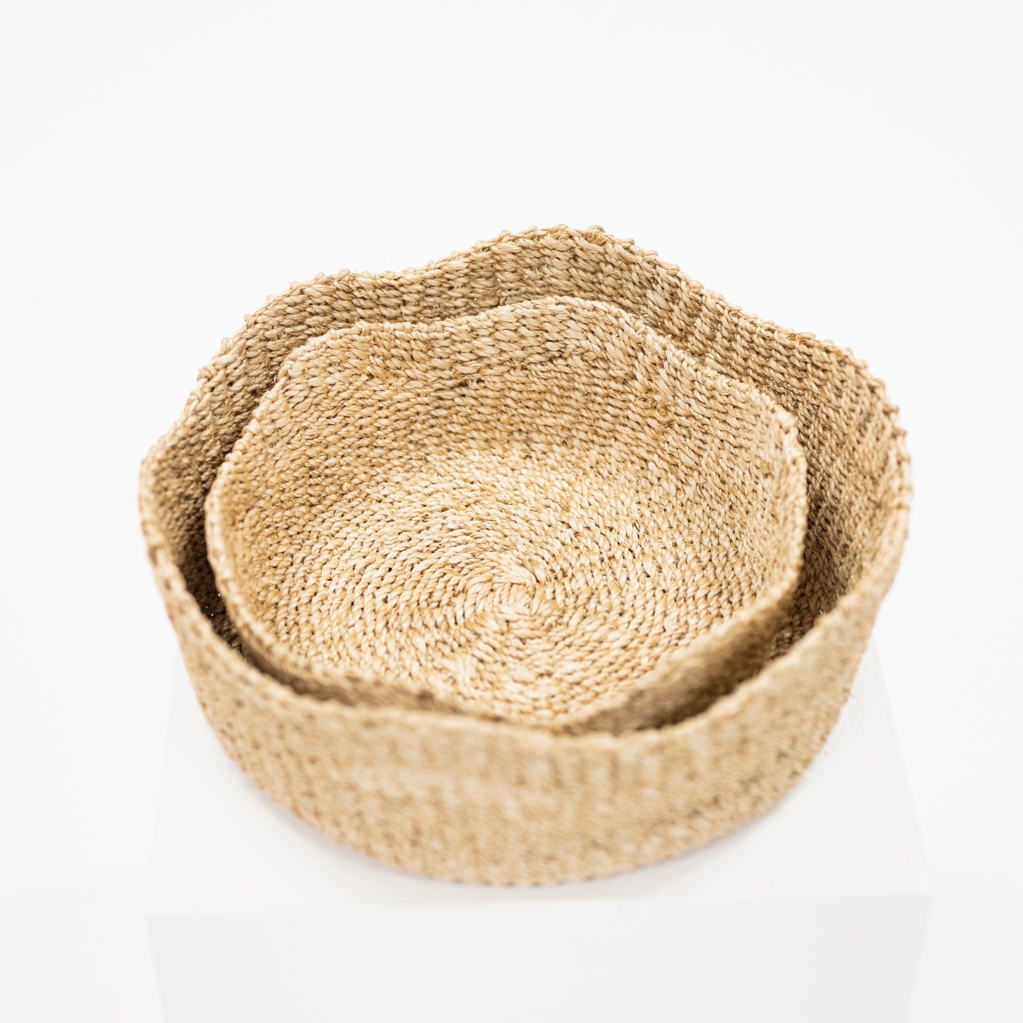 Two nested round woven baskets made of natural jute or seagrass, shown on a clean white background.