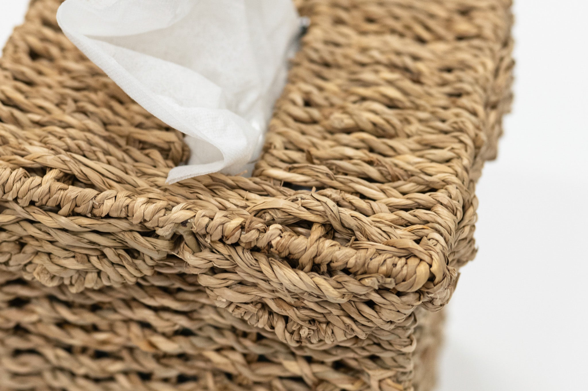 Woven basket with a white tissue inside on a light background