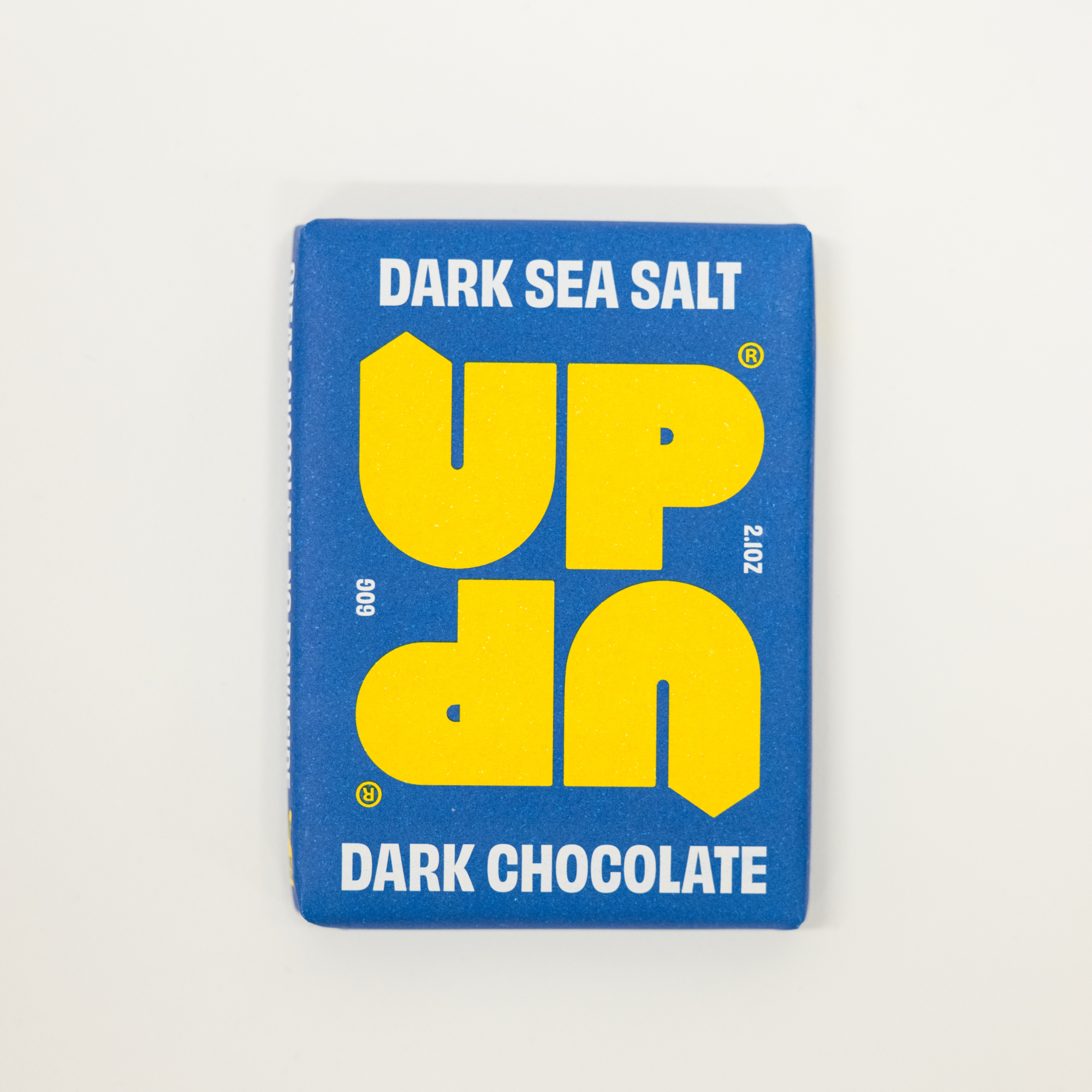 Blue and yellow chocolate bar packaging with 'UP' branding on a light gray background