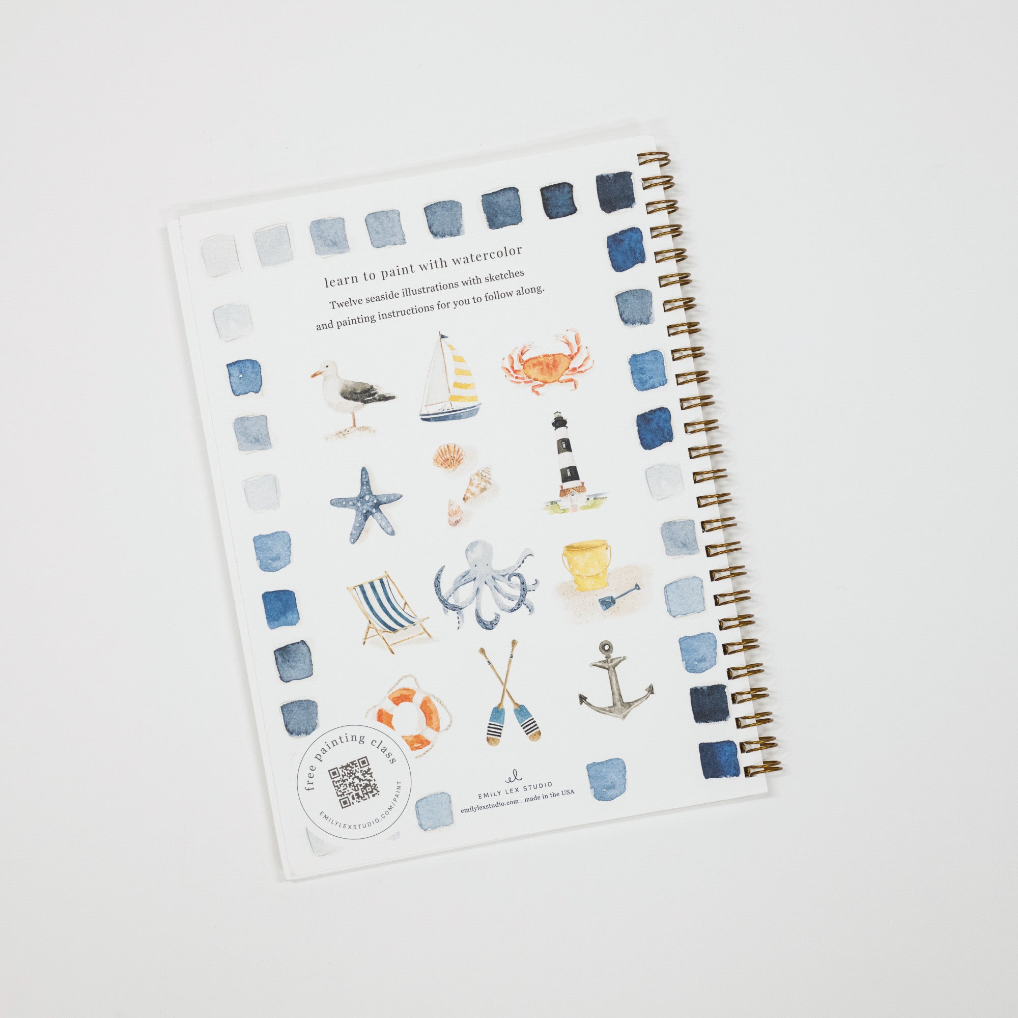 A spiral-bound watercolor painting guide book titled 'Learn to paint with watercolor' by Julia Lee, featuring a nautical theme with illustrations of a sailboat, crab, lighthouse, starfish, octopus, anchor, and striped beach chair, displayed on a light gray background.