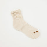 A single cream-colored ribbed knit sock with a contrasting brown toe cap, displayed on a clean white background.