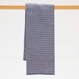 Gray blue textured towel hanging on a wooden rod against a white background