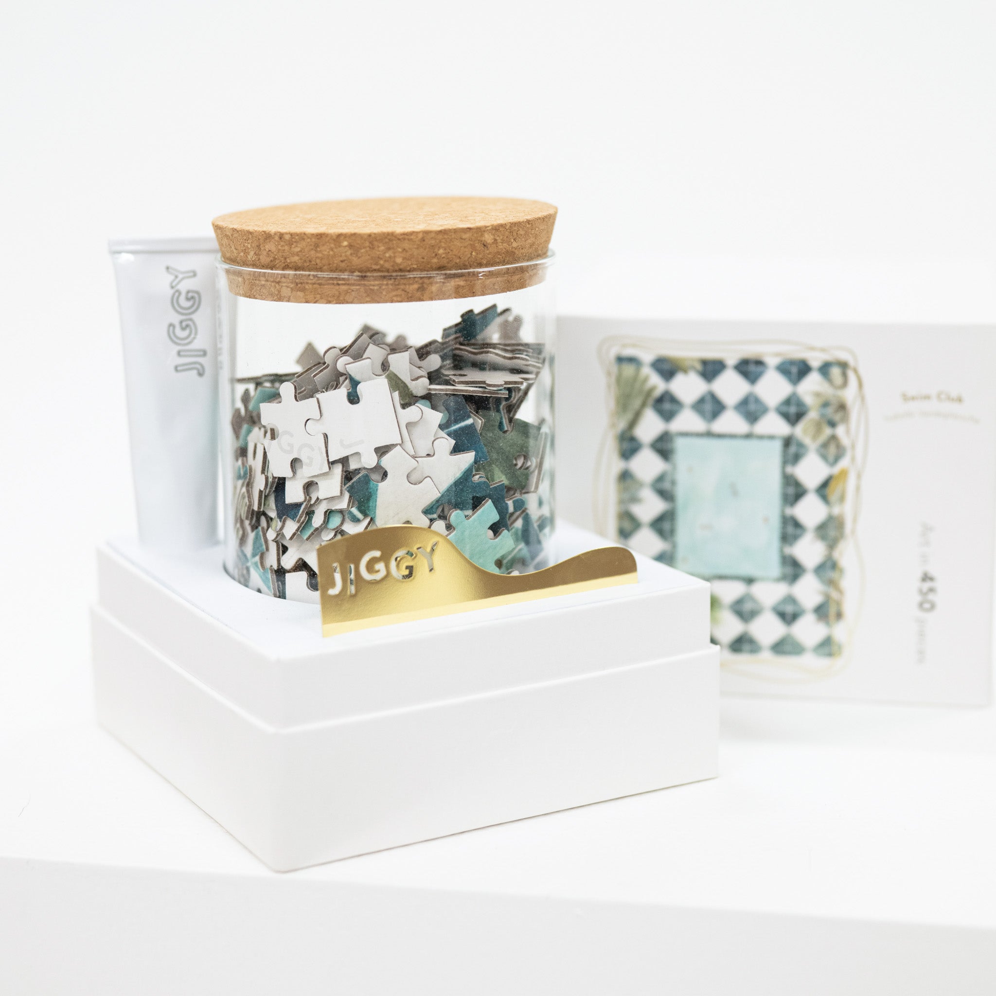 Jigsaw puzzle pieces in a container with 'JIGGY' branding on a white background