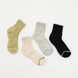 Four ribbed ankle socks laid flat on a white background: one olive green, one cream, one heather gray, and one black, each with a contrasting accent line near the toe.