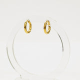 Gold hoop earrings on a clear stand against a white background