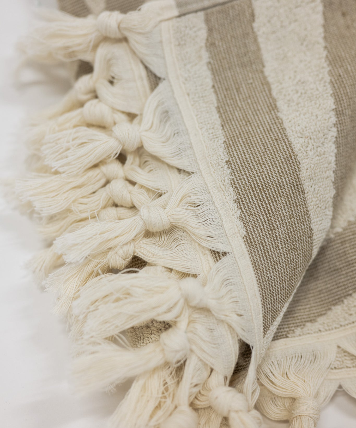 Close-up of a beach towel with tassels on a white background