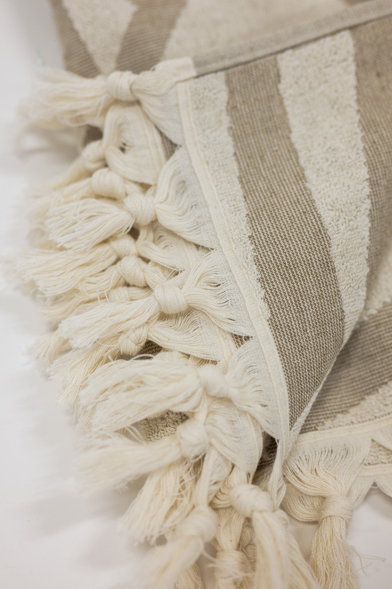 Close-up of a beach towel with tassels on a white background
