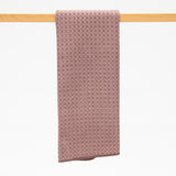 Taupe textured kitchen towel hanging on a wooden rod against a white background