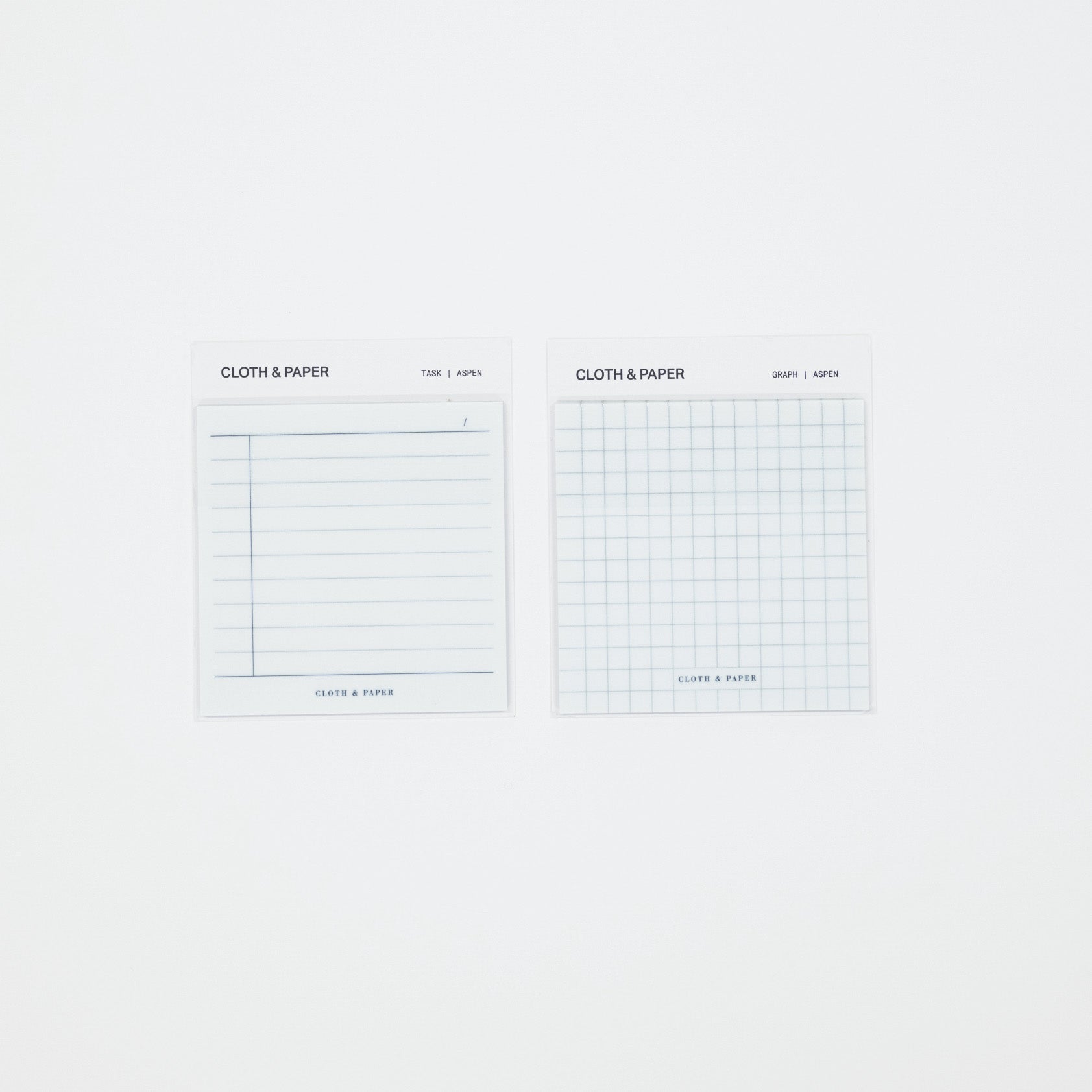 Two small white paper pads labeled CLOTH & PAPER, one with horizontal lines and one with a light blue grid, shown on a plain white background.