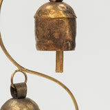Two brass bells hanging from a curved brass rod on a white background