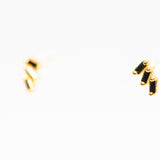 Gold earrings with black accents on a white background