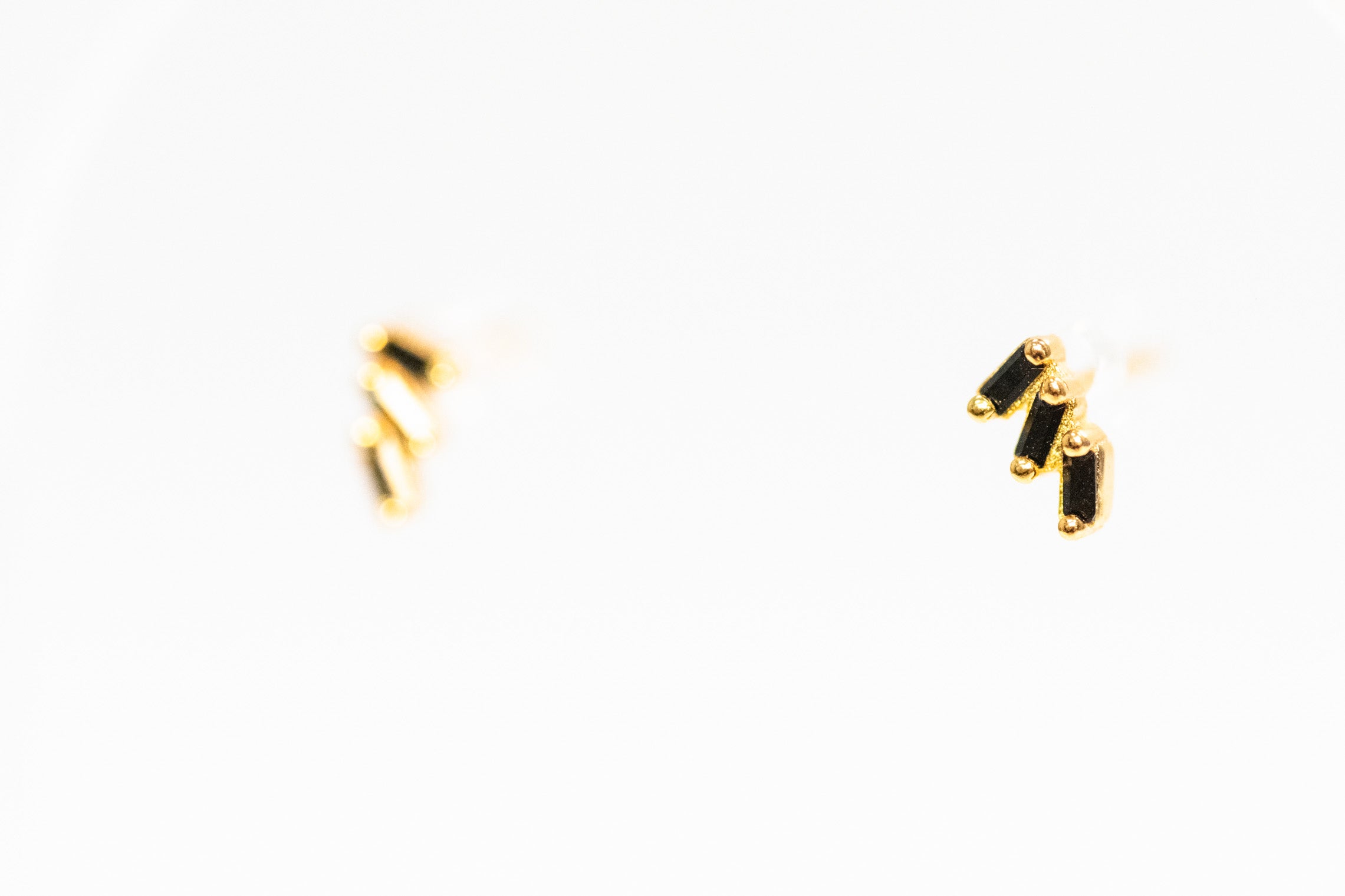 Gold earrings with black accents on a white background