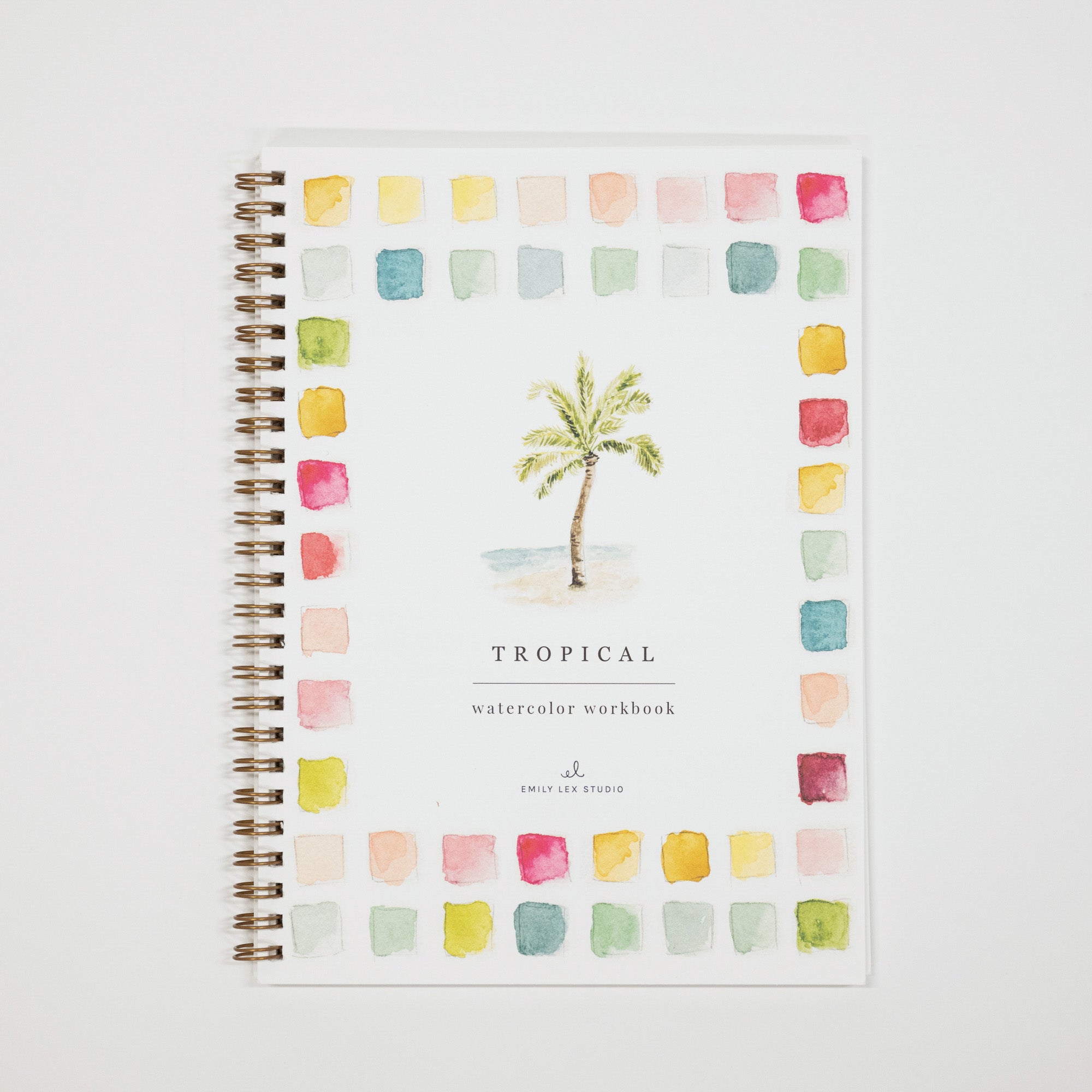 A spiral-bound watercolor workbook titled 'TROPICAL watercolor workbook' by Smile of a Studio, featuring a central palm tree illustration surrounded by a border of pastel watercolor swatches on a white cover.