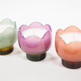 Three colorful glass candle holders with candles inside on a white background