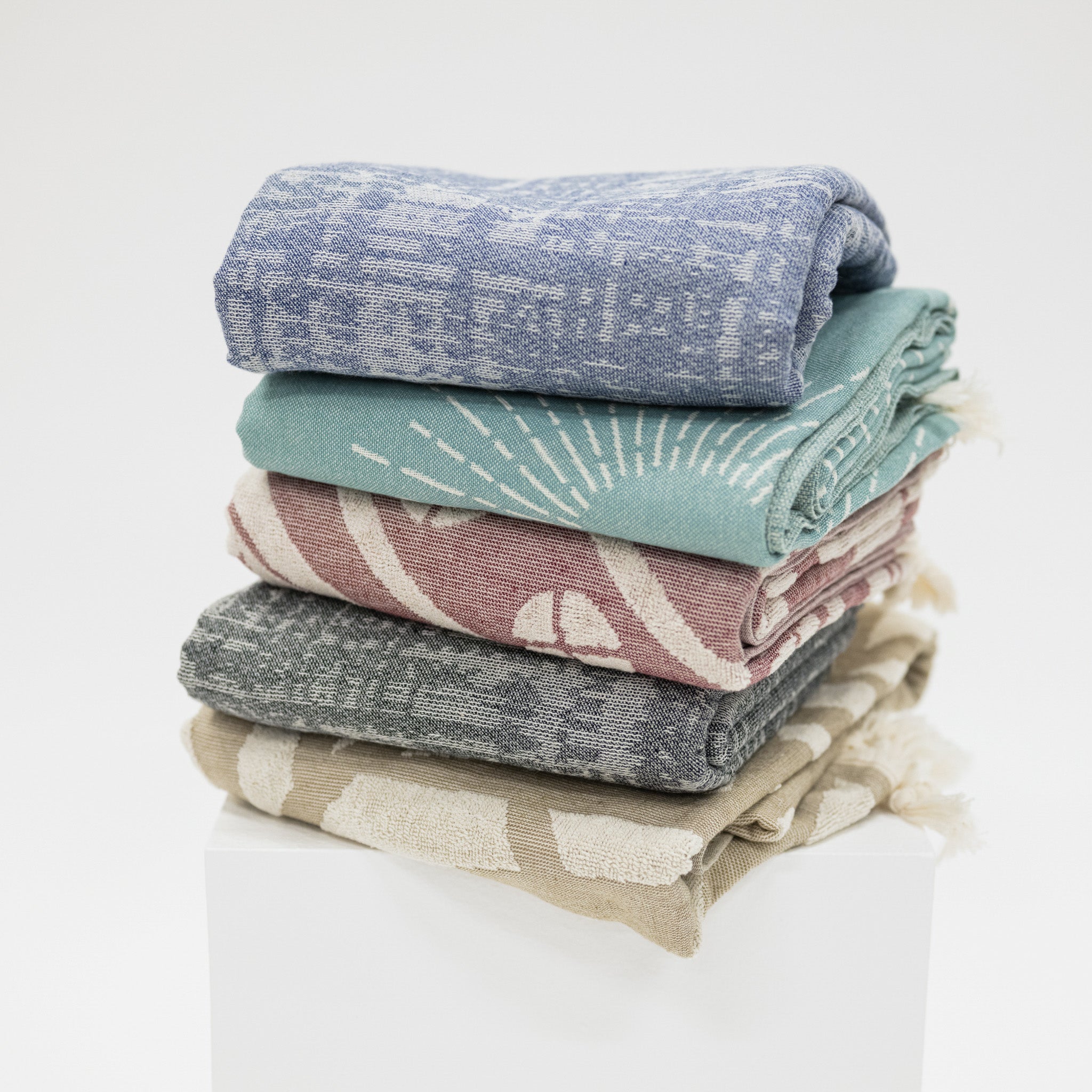 Stack of folded beach towels in various colors on a white background