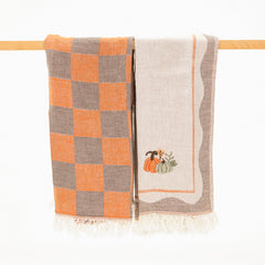 pair of fall turkish cotton towels with taupe and orange. One with a checkerboard pattern and one with a pair of embroidered pumpkins.