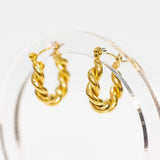 Gold hoop earrings on a clear stand against a white background