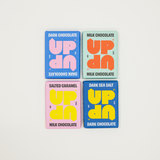 Four chocolate bars with colorful packaging on a light gray background