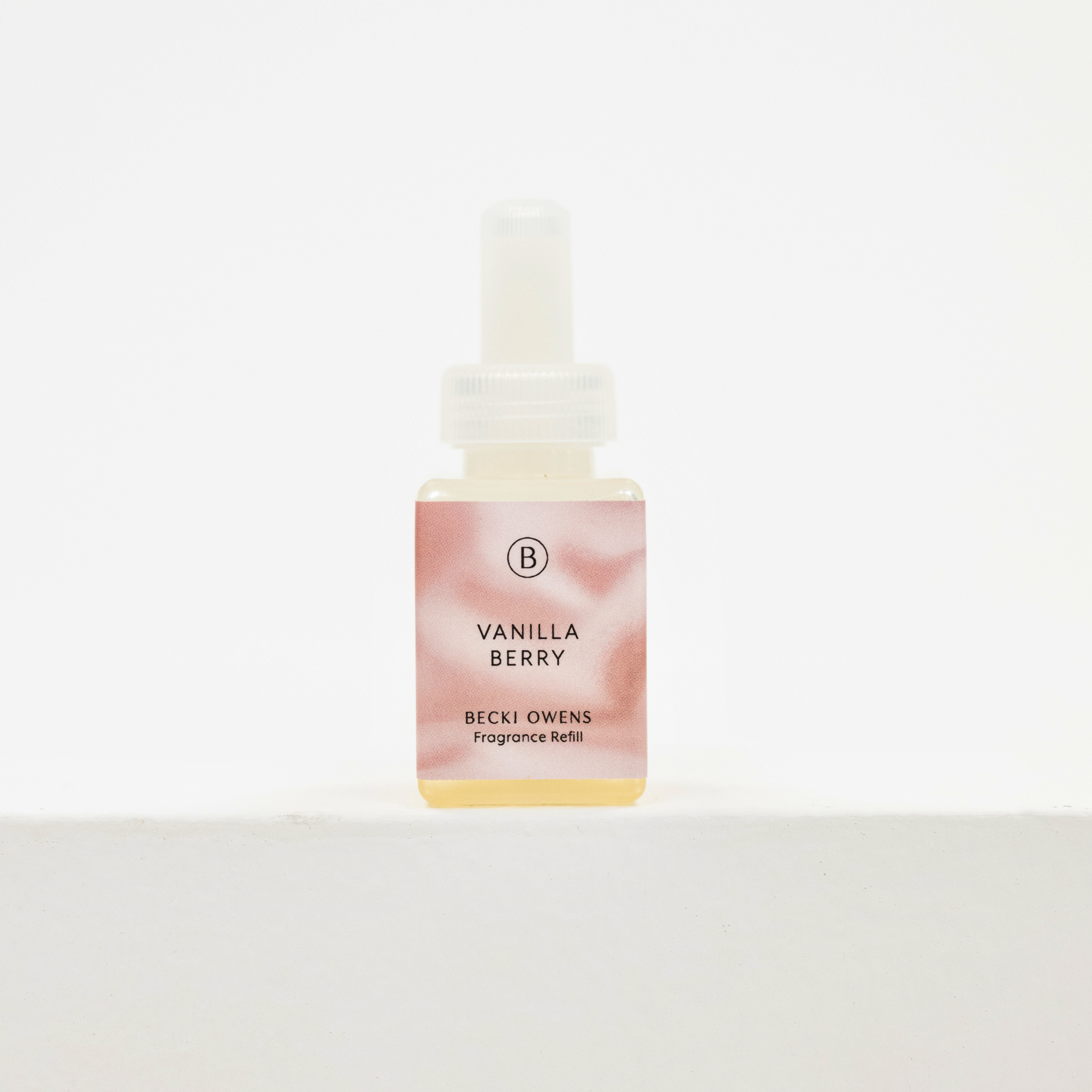 A small square bottle of fragrance oil with a white dropper cap, featuring a pink and peach marbled label that reads 'VANILLA BERRY' and 'BECKI OWENS Fragrance Oil' for Pura