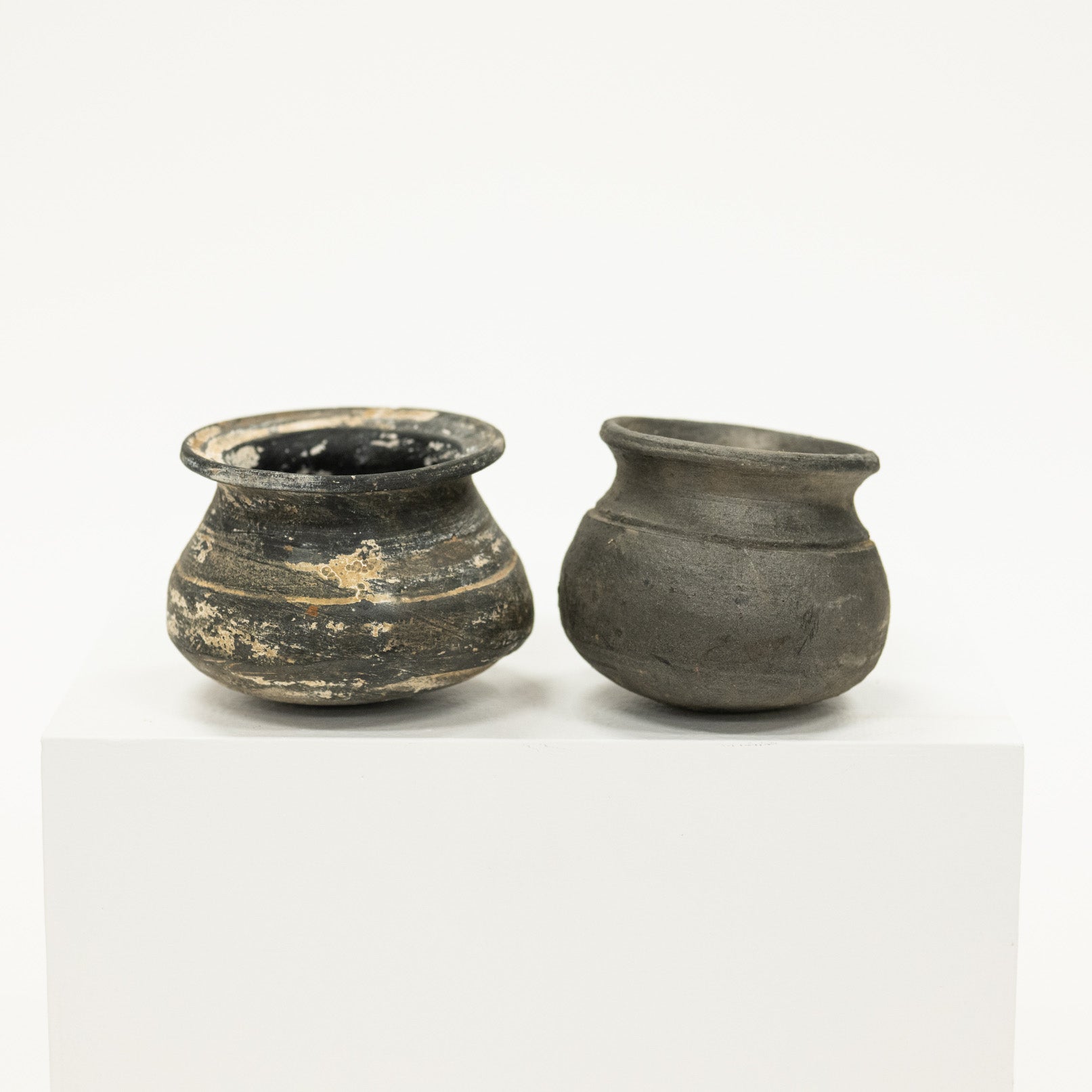 Two small black ceramic pots on a white background