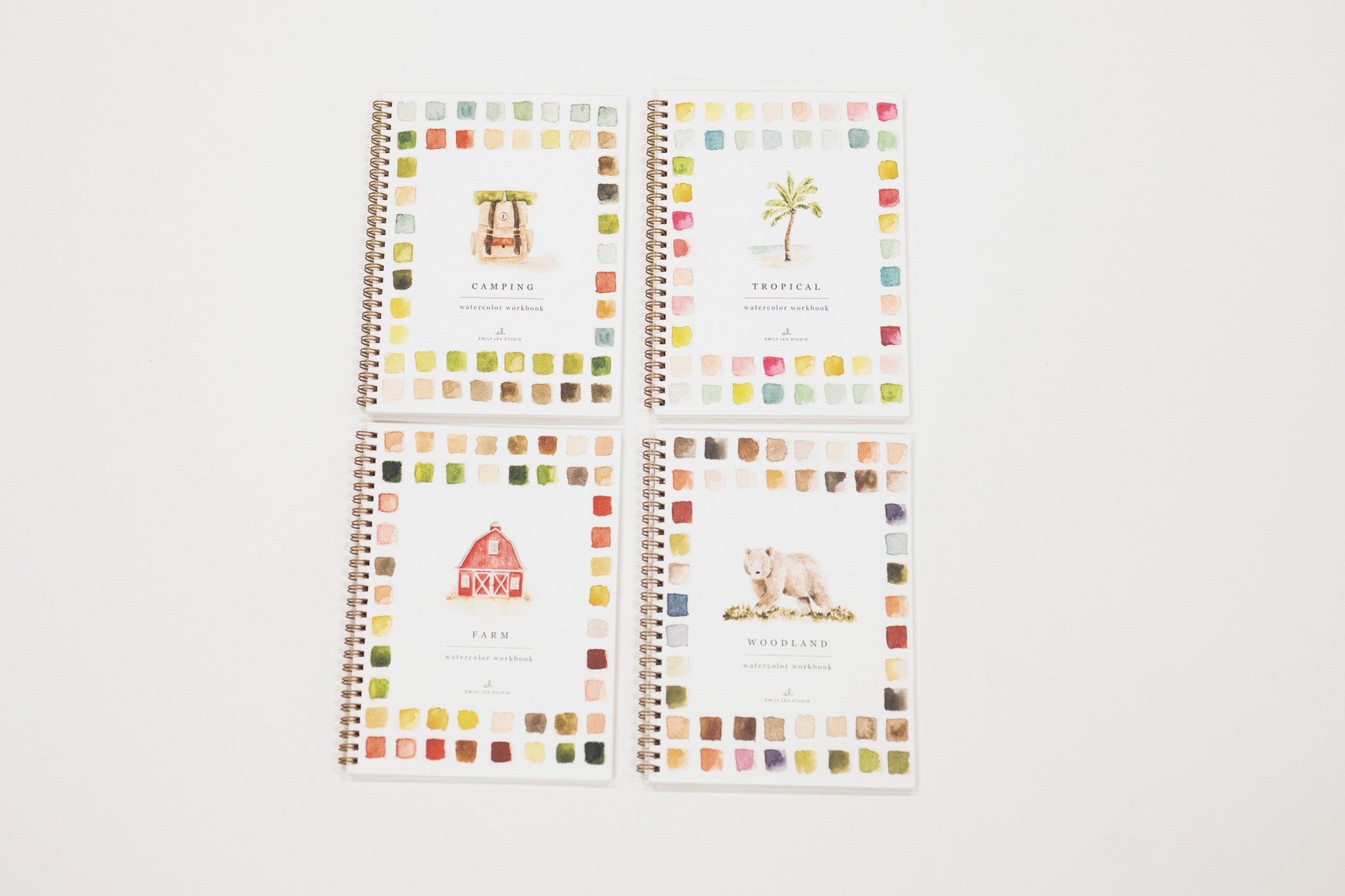 Set of four spiral-bound notebooks with colorful square patterns on a white background