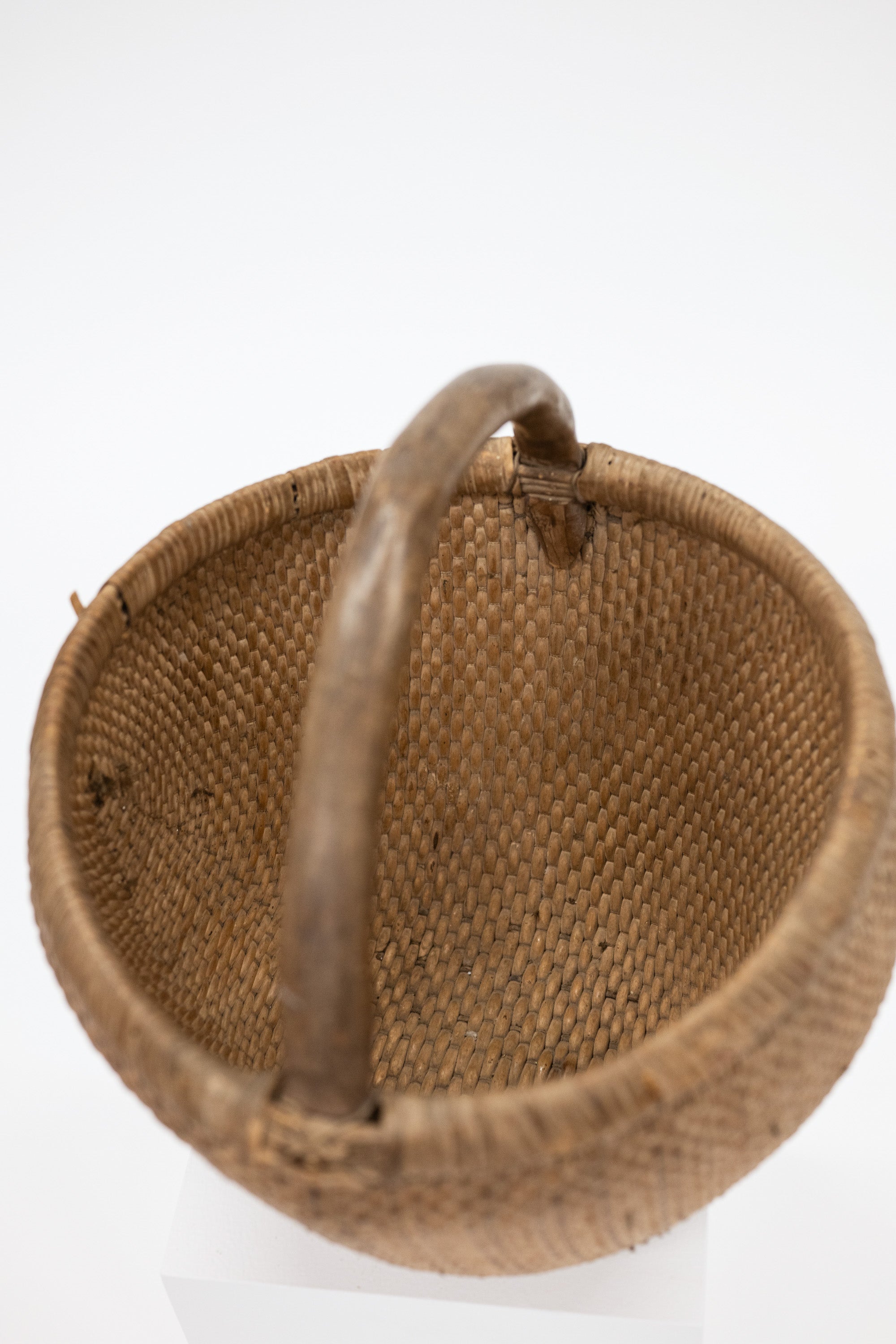 Brown woven basket with a handle on a white background