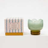 Green glass tulip shaped candle with a box featuring decorative patterns on a white background
