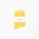 mustard yellow cloud socks on a white surface, each with a label indicating the brand le bon shoppe