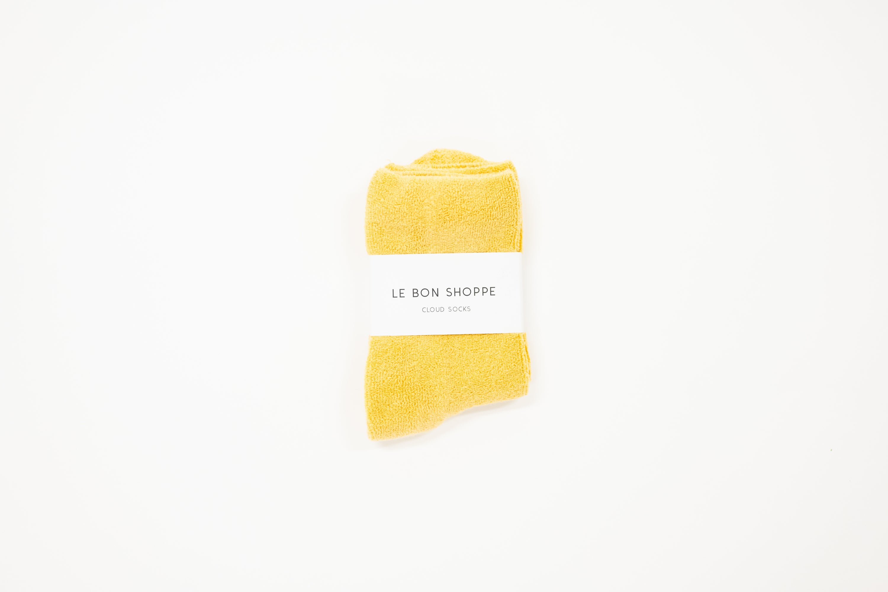 mustard yellow cloud socks on a white surface, each with a label indicating the brand le bon shoppe
