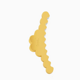 A gold-colored hair claw clip with a scalloped, wavy design, shown on a plain white background.