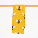 a yellow microfiber kitchen towel with a pattern of black and white bees